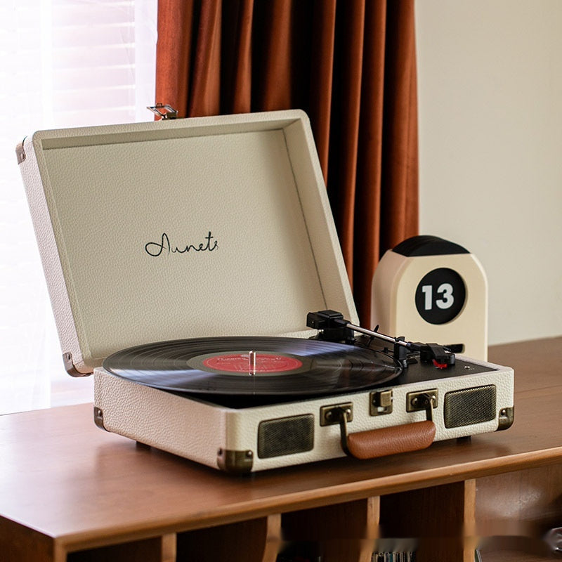 Vintage suitcase turntable playing a record on a wood shelf - Audio Headphones & Music Gear